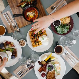 Woman reaching for syrup at brunch table with three other friends in Old City
